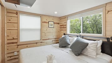 Ein Zimmer mit Holzwänden, einem Bett, einem Fenster und einem Bild an der Wand.