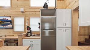 A modern kitchen with wooden walls, a stainless steel refrigerator, and a coffee machine. - Chama Crossing - Tiny Train Next to Railroad (Chama)