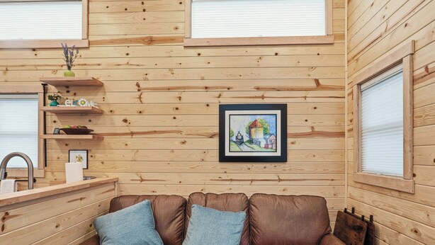 A wooden interior with a brown leather sofa, a framed picture, and a window with blinds. - Chama Crossing - Tiny Train Next to Railroad (Chama)