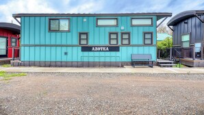 A turquoise building with the sign 'AZOTEA' on the front, featuring multiple windows and a bench outside. - Chama Crossing - Tiny Train Next to Railroad (Chama)