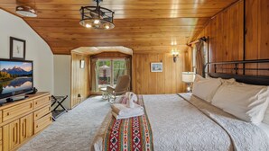 A wooden-paneled room with a bed, a television, and a desk. - Chama Crossing - Historic Home next to Railroad (Chama)