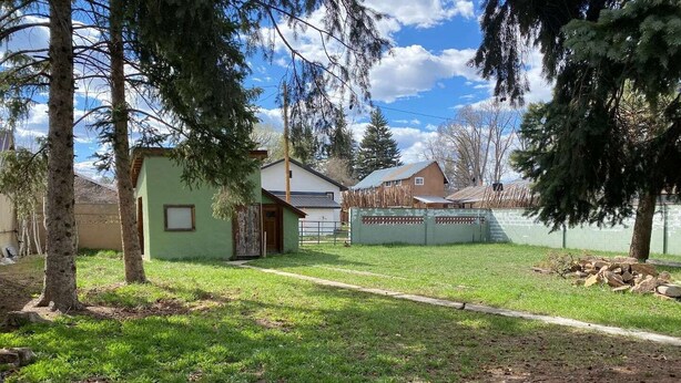 A residential area with a green house, a fenced yard, and a clear sky. - Chama Crossing - Historic Home next to Railroad (Chama)