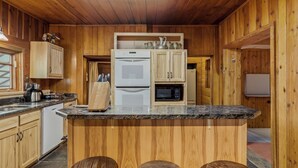 A kitchen with wooden cabinets, a refrigerator, a microwave, and a coffee maker. - Chama Crossing - Historic Home next to Railroad (Chama)