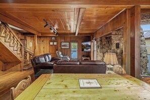 A cozy cabin interior with a wooden staircase, leather sofa, and a dining table with a placemat. - Chama Crossing - Historic Home next to Railroad (Chama)