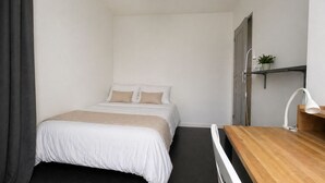 A bedroom with a bed, a wooden desk, a shower, and a hanging light fixture. - Cosy & Welcoming Apartment – City Center – Sleeps 3/4 (Angers)