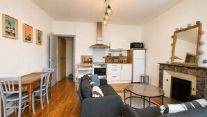 A compact living space with a dining area, sofa, kitchen, and a fireplace. - Cosy & Welcoming Apartment – City Center – Sleeps 3/4 (Angers)
