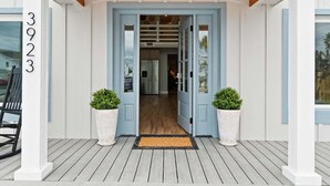 A house entrance with a wooden porch, a blue door, and two potted plants. - Fall Deals + Snowbird Rates | Coastal Stay Near the Beach (Panama City Beach)
