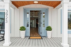 A house entrance with a wooden porch, a blue door, and two potted plants. - Fall Deals + Snowbird Rates | Coastal Stay Near the Beach (Panama City Beach)