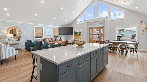 A spacious living area with a large island, a dining table, and a kitchen with grey cabinetry. - Fall Deals + Snowbird Rates | Coastal Stay Near the Beach (Panama City Beach)