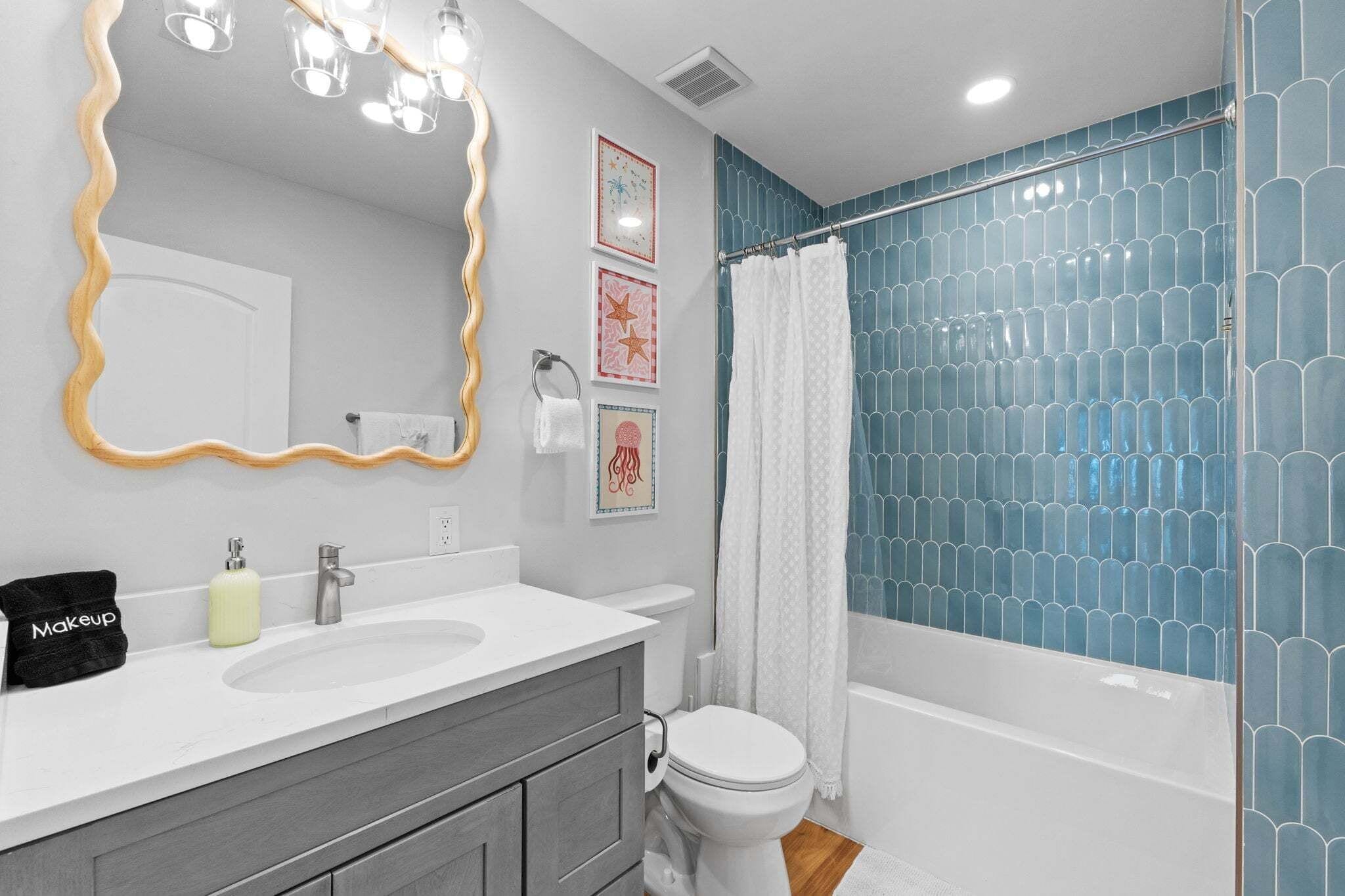 A bathroom with a vanity, sink, mirror, and shower.