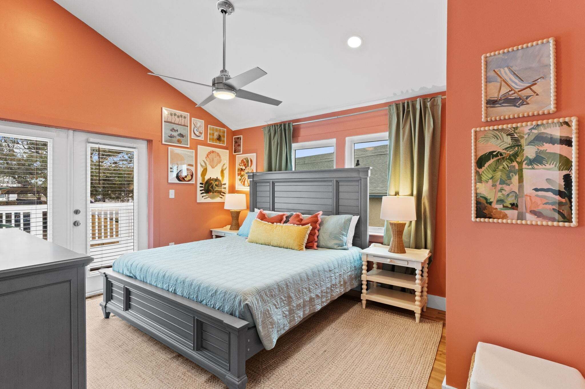 A bedroom with a bed, a ceiling fan, a nightstand, a lamp, and artwork on the walls.