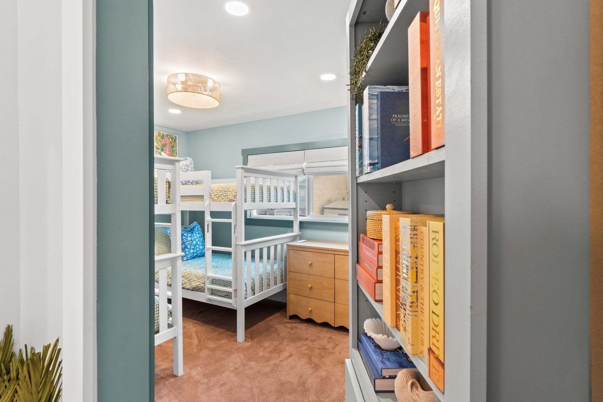 Una habitación infantil con literas, una estantería y un escritorio pequeño.