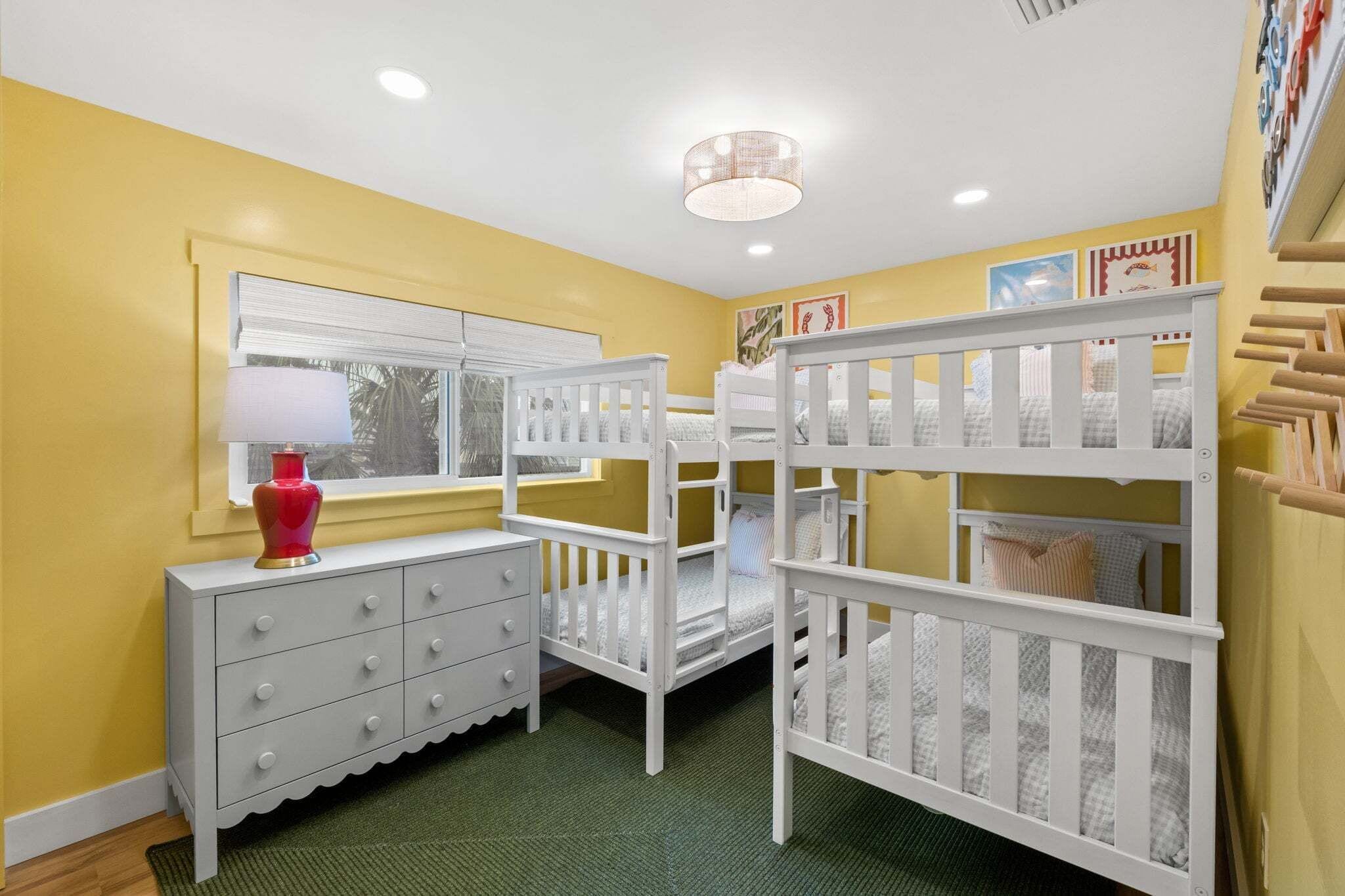 A room with a crib, a dresser, and a window with blinds.