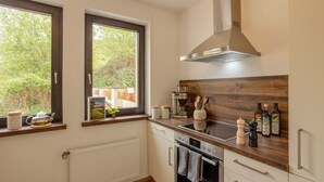 A kitchen with a window, a stove, a microwave, and a wooden countertop. - Hunter's Lodge Adventure | Hot Tub I Wild Views (Gerolstein)