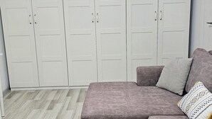 Huoneessa on suuri vaatekaappi, sohva ja kalanruotokuviollinen lattia.