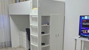 Huoneessa on kerrossänky, työpöytä, tuoli, televisio ja sohva.