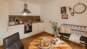 Eine kompakte Küche mit modernen Geräten, ein Essbereich mit einem Holztisch und eine gemütliche Sitzecke mit einer Couch.