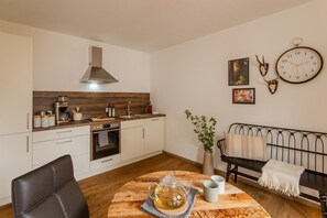Eine kompakte Küche mit modernen Geräten, ein Essbereich mit einem Holztisch und eine gemütliche Sitzecke mit einer Couch.