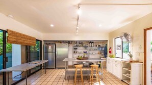 Une cuisine moderne dotée d’appareils électroménagers en acier inoxydable, d’un îlot central avec des tabourets et offrant une vue sur l’extérieur.