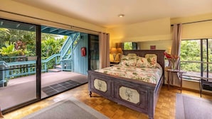 Une chambre à coucher comprenant un lit, une table de chevet, une fenêtre avec des rideaux, une vue sur la verdure à l’extérieur et un escalier menant à un espace extérieur.