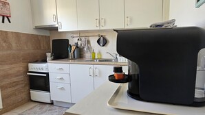 Keittiössä on valkoiset kaapit, liesi, pesuallas ja musta kodinkone, joka on asetettu alustalle.