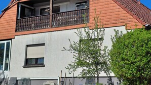 A two-story house with a red-tiled roof, a balcony with a metal railing, and a white exterior wall. - Vacation apartment with a view (Joachimsthal)