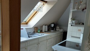 A kitchen with white cabinets, a skylight, and a white countertop with various items. - Vacation apartment with a view (Joachimsthal)