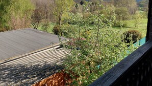 A view from a covered outdoor area with a metal roof, surrounded by greenery and trees. - Vacation apartment with a view (Joachimsthal)