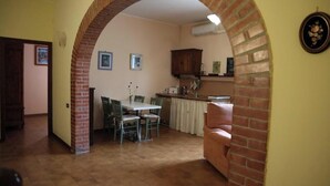 A dining area with a brick archway, a table with chairs, and a kitchen in the background. - Casa Teo:  Relaxation and Culture  in the Heart of Tuscany (Toscana)