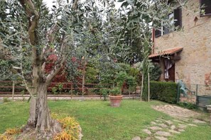 Ein Steinhäuschen mit Garten, Baum und Blumentopf.