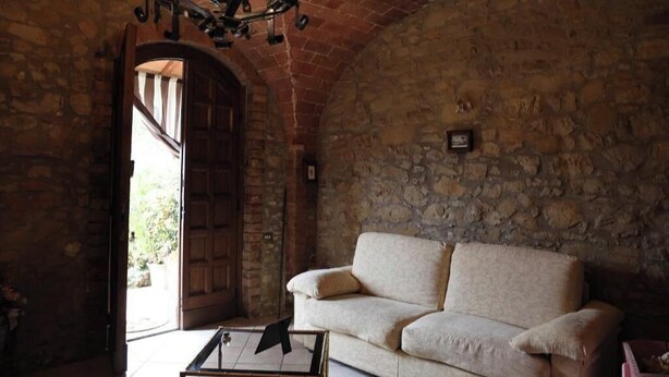 A stone-walled room with a wooden door, a beige sofa, and a glass coffee table. - Casa Teo:  Relaxation and Culture  in the Heart of Tuscany (Toscana)
