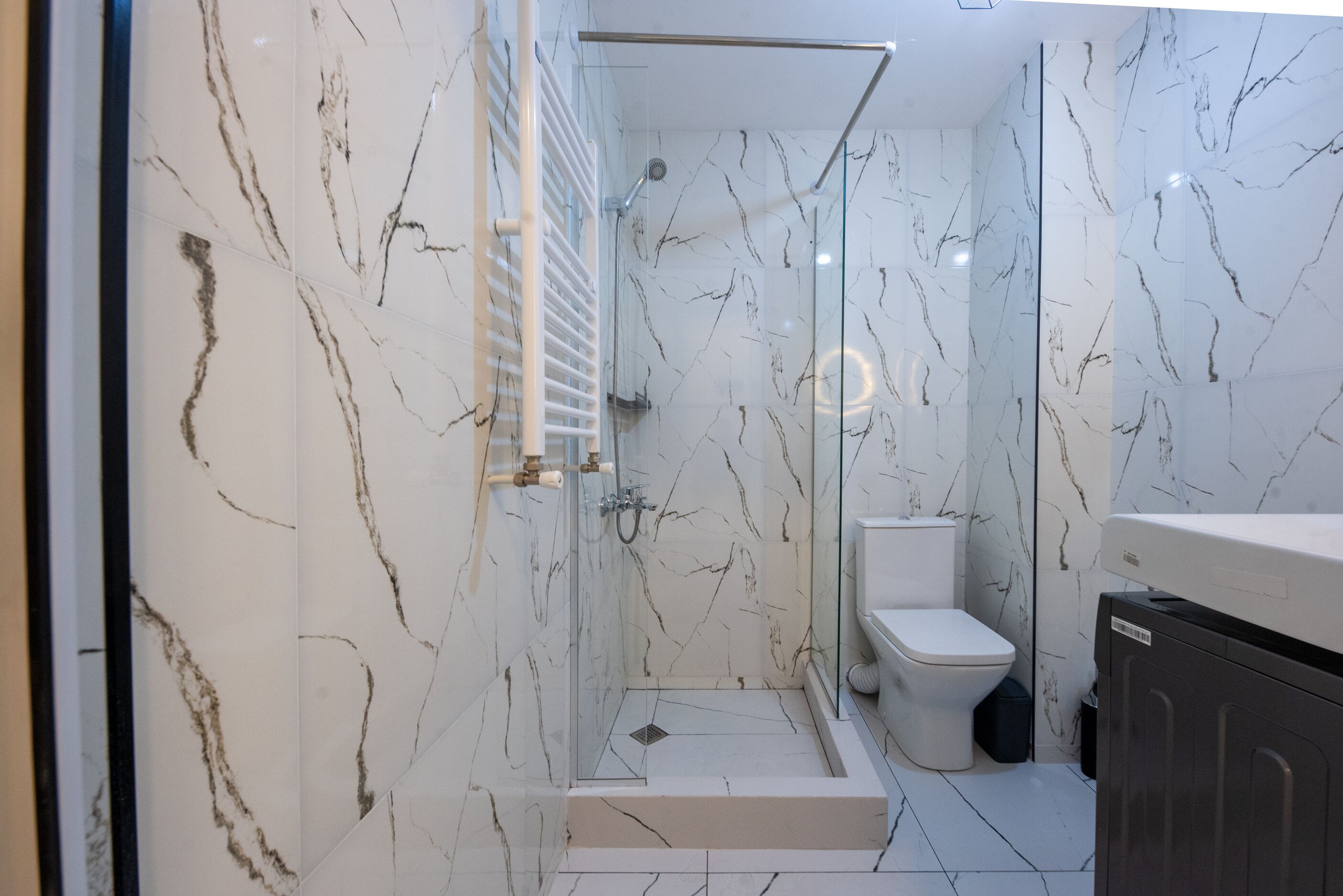 Un baño moderno con ducha de vidrio, inodoro y tocador con gabinete.