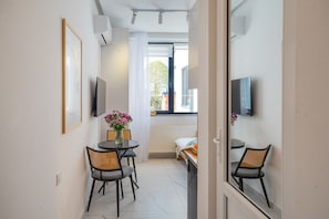 A compact room with a bed, a small table with chairs, a TV mounted on the wall, and a window with a view of the outside. - HB apartments Chitadze (Tbilisi)