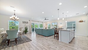 A spacious living area with a large sofa, dining table, and kitchen island. - Emerald by the Sea at Lost Key Golf & Beach Club | Resort Amenities | Beach Shuttle | Beach Getaways (Pensacola)