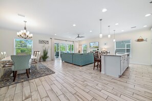A spacious living area with a large sofa, dining table, and kitchen island. - Emerald by the Sea at Lost Key Golf & Beach Club | Resort Amenities | Beach Shuttle | Beach Getaways (Pensacola)