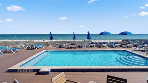 A pool area with lounge chairs and umbrellas, a clear view of the ocean, and a deck with a railing. - Emerald by the Sea at Lost Key Golf & Beach Club | Resort Amenities | Beach Shuttle | Beach Getaways (Pensacola)