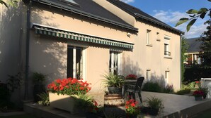 A house with a patio, potted plants, and a chair. - Chambre Bleue Guest Room with Shared Terrace, Garden, and Wi-Fi (Saint-Avertin)