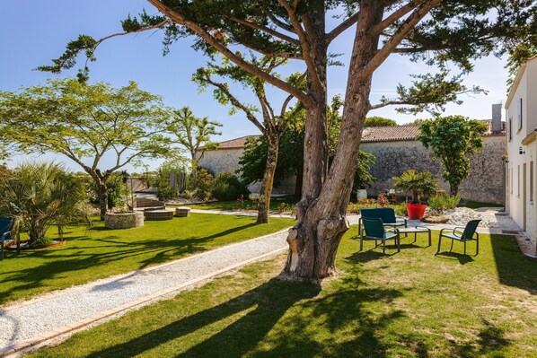 A courtyard with a gravel path, green lawn, and outdoor seating area with chairs and a table.