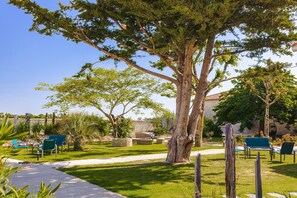 A garden with a large tree, outdoor seating, and a stone wall.