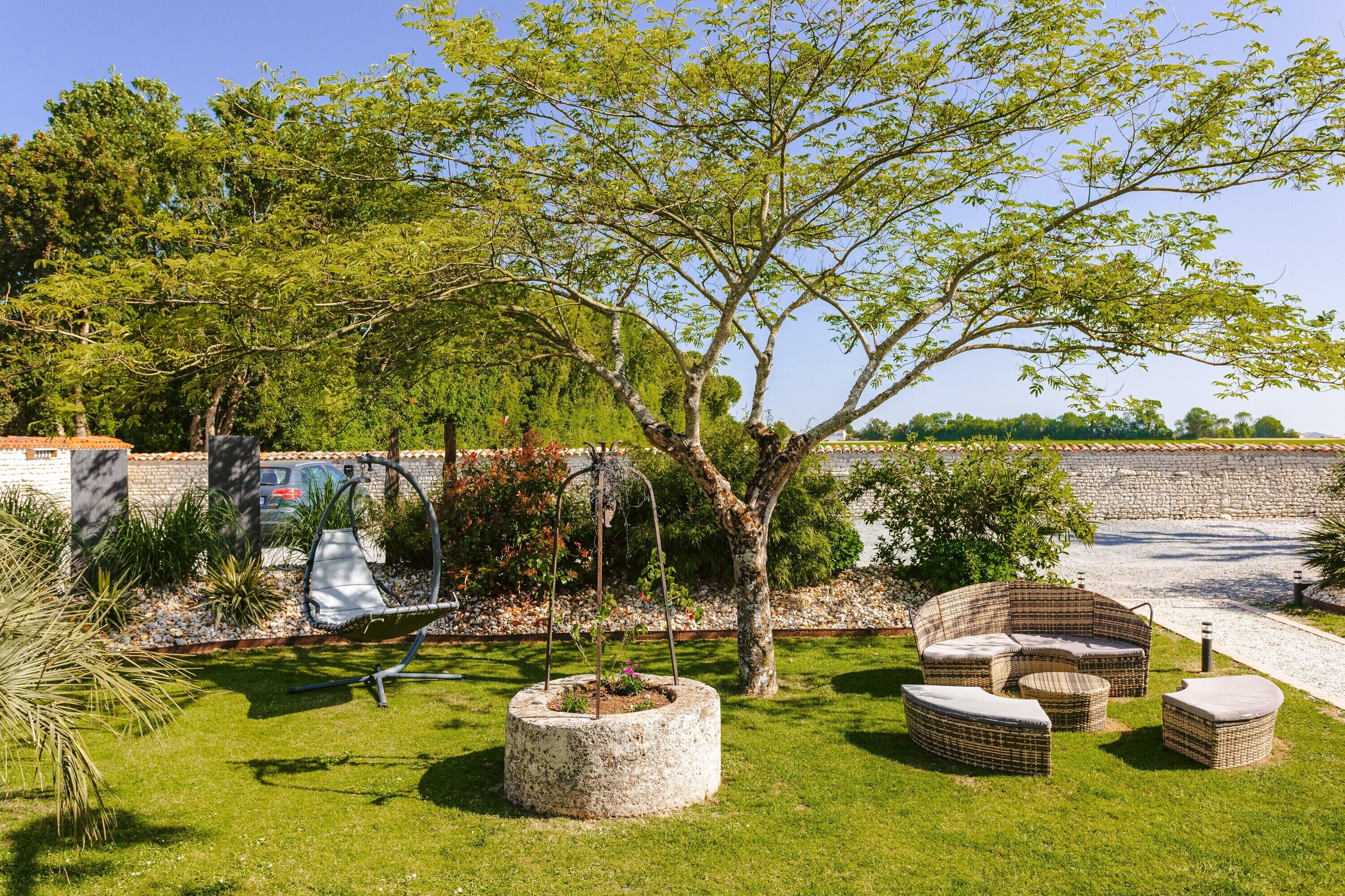 Un jardin aménagé avec du mobilier d’extérieur, un hamac et un arbre.