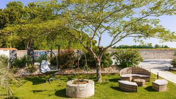 Un jardin aménagé avec du mobilier d’extérieur, un hamac et un arbre.