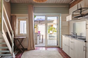A kitchen with a sliding glass door leading to an outdoor area, a small table with a chair, and a staircase.