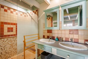 A bathroom with two sinks, a shower, and a mirror.