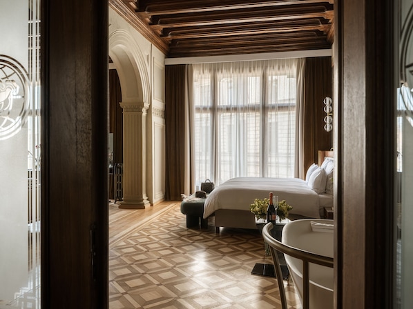A hotel room with a bed, a round table, a chair, a window with curtains, and a patterned floor. - The House 14 (Kraków)