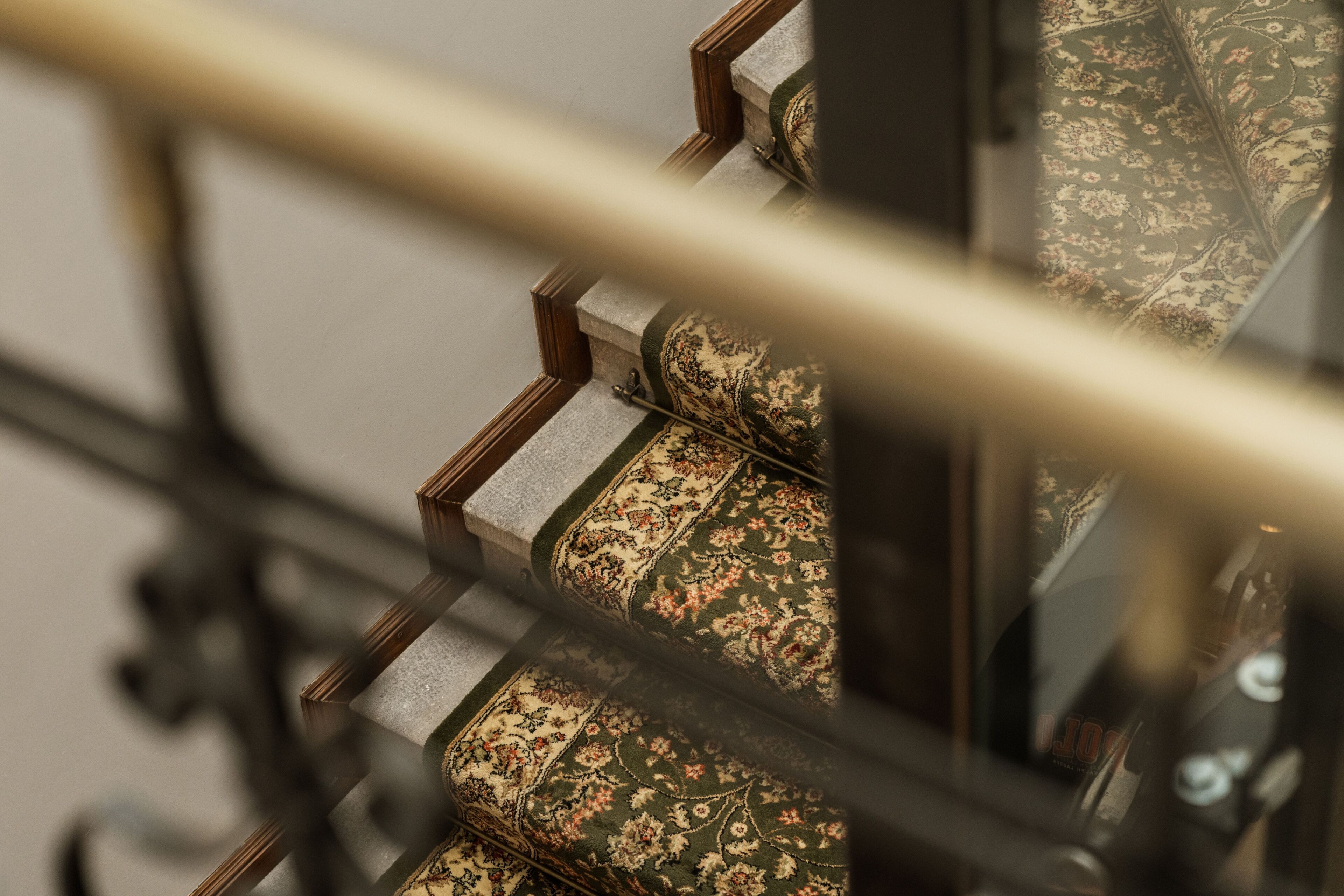 Una escalera con peldaños alfombrados y barandilla de metal.