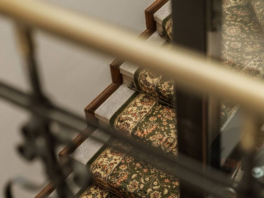 Una escalera con peldaños alfombrados y barandilla de metal.