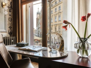 A room with a view of a cityscape, a table with a book and glasses, a vase with flowers, and a radiator. - The House 14 (Kraków)