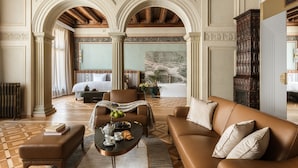 Una habitación amplia con una cama grande, un área de descanso con una mesita de café y vistas a un balcón.