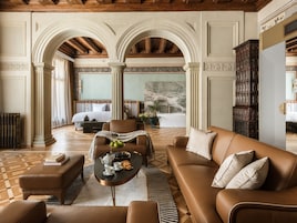A spacious room with a large bed, a sitting area with a coffee table, and a view of a balcony.