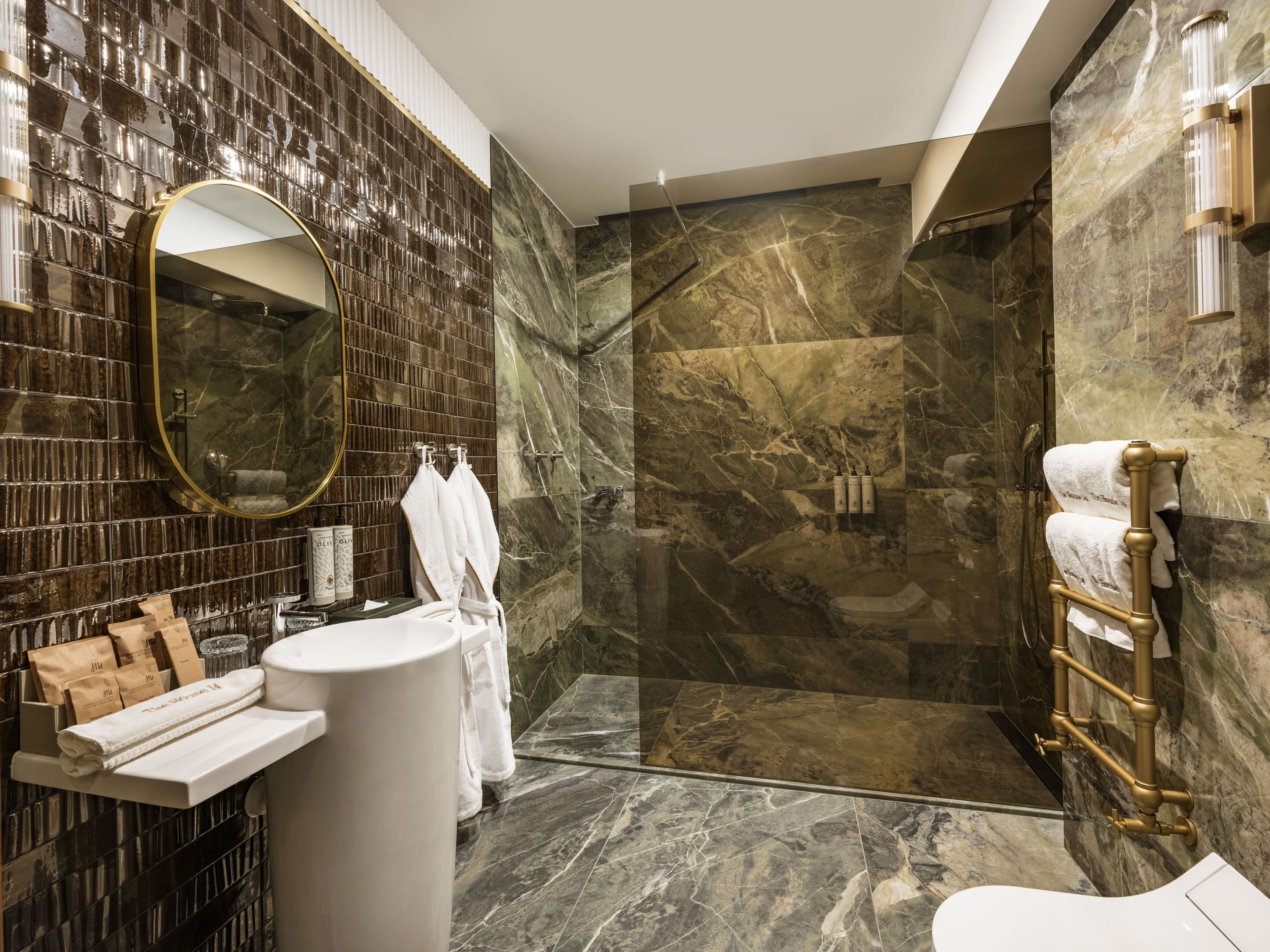 Een moderne badkamer met een douche van marmer, een ronde spiegel en een witte wastafel.